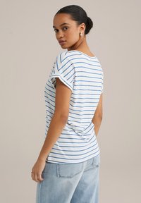 Striped short-sleeve T-shirt in white with blue stripes; relaxed fit; made of soft fabric; paired with light blue denim jeans.