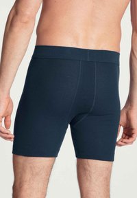 Donkerblauwe boxershorts van zachte stof, met een brede elastische tailleband, een gladde textuur en zonder zichtbare patronen of hardware-details.