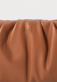 Brun läderhandväska med mjuk rynkad textur och präglad "MM"-logotyp centrerad på den släta ytan.