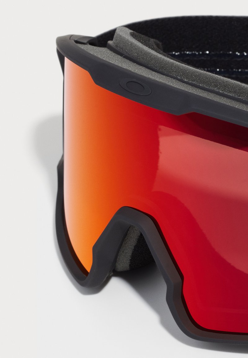 Lunettes de ski avec une grande lentille orange miroir, un cadre en caoutchouc noir et un rembourrage en mousse texturée. Elles possèdent un design courbé pour un ajustement ergonomique.