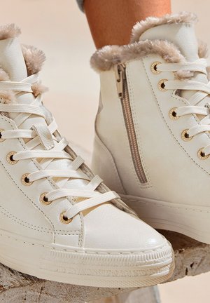 White high-top sneakers made of leather, featuring faux fur trim, gold hardware accents, a side zipper, and white laces.