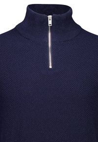 Dunkelblaues Pullover mit hohem Kragen, strukturiertem Stoff und kurzem Reißverschluss vorne. Das Strickmuster verleiht dem Design Tiefe.
