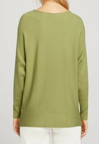 Grün gestrickter Pullover mit lockerer Passform, breitem Ausschnitt und langen Ärmeln. Die Textur ist weich und das Design minimalistisch.