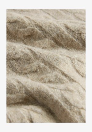 Beige gebreide stof met een textuur van kabelpatroon. Het oppervlak lijkt zacht en wollig, met subtiele variaties in kleur en diepte.