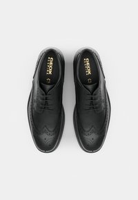 Pantofi eleganți din piele neagră, cu detalii brogue, textură netedă, vârf rotund și sistem de închidere cu șireturi. Prezintă brandingul "GEOX RESPIRA".