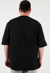 Černé bavlněné tričko s krátkými rukávy a rovním lemem, s jednoduchým designem a bez viditelných log či vzorů.
