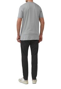 Szara bawełniana koszulka z krótkim rękawem, w zestawie z czarnymi spodniami i białymi trampkami. Koszulka ma klasyczny okrągły dekolt i luźny krój.
