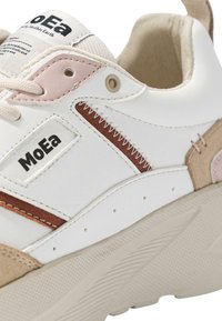 Witte sneaker met beige en roze accenten, van leer en suède materialen, met gestikte details, logo op de zijkant en een getextureerde zool.