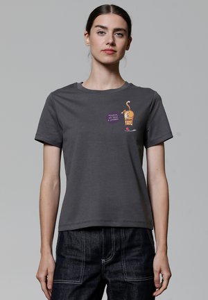 T-shirt en coton gris avec un col ras du cou. Présente un graphique cartoon d'un chien avec une glace et le texte "Houston, nous avons un problème." Manches courtes.