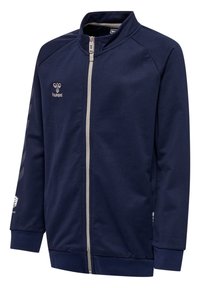 Veste zippée marine en tissu doux, dotée d'un col montant, d'une fermeture éclair contrastante, et d'un logo sur la poitrine et la manche avec des rayures diagonales.