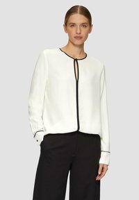 Witte blouse met zwarte piping, met een ronde hals en uitsparing. Lange mouwen met knoopmanchetten, zachte stof en een comfortabele pasvorm.
