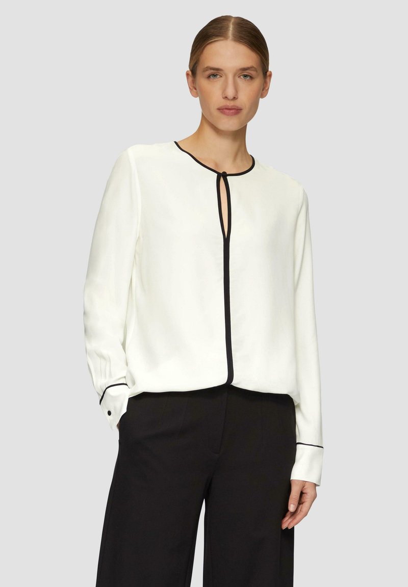 Witte blouse met zwarte piping, met een ronde hals en uitsparing. Lange mouwen met knoopmanchetten, zachte stof en een comfortabele pasvorm.