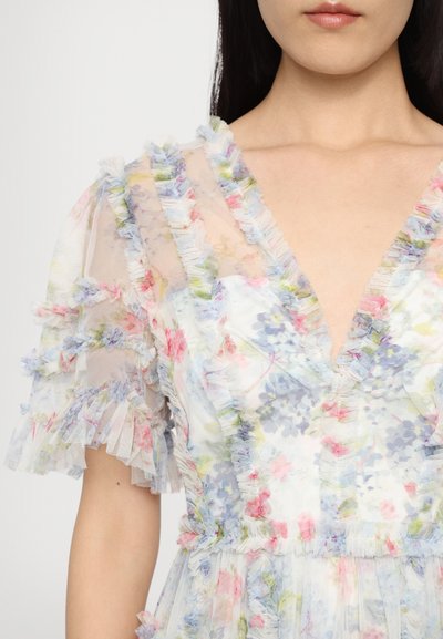 Bloemenprint jurk met korte mouwen van doorschijnende stof en een gerimpelde afwerking. Kleuren zijn lichtblauw, roze en groen. Heeft een diepe V-hals.