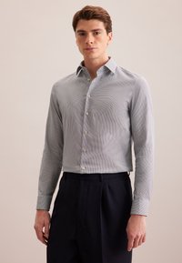 Camicia a bottoni azzurro chiaro con motivo, maniche lunghe, colletto alla francese e bottoni simili a perle, abbinata a pantaloni scuri.