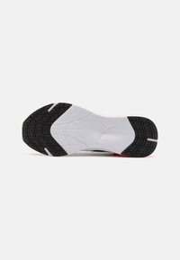 Athletic shoe sole featuring a black rubber tread pattern with a white midsole, accented by a visible logo and smooth texture.