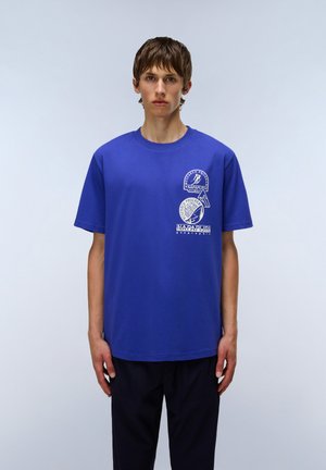 Blå bomulds T-shirt med rund halsudskæring, der har tre hvide grafiske tryk, inklusive tekst og logo detaljer på forsiden.