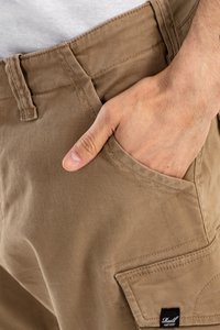 Pantalones cargo de algodón marrón con bolsillos laterales, con un corte recto y detalles de costura visibles. Lleva una etiqueta con "Reell".