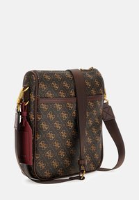Brązowa torebka na ramię z wzorem, z złotymi okuciami, wyposażona w pasek na ramię oraz bordowy akcent w postaci saszetki. Teksturowana powierzchnia z logo.