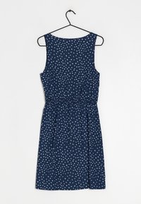 Granatowa sukienka bez rękawów z białym wzorem w rozsypane kropki, elastyczny pas, spódnica do kolan, wisząca na czarnym plastikowym wieszaku.