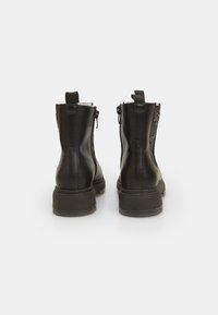 Črne usnjene gležnjarje s teksturiranim panelom in debelimi podplati. Imajo zadrge na obeh straneh in zanke na zadnji strani za lažje obuvanje.