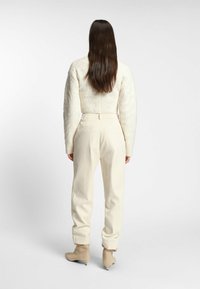 Light cream textured sweater with a cropped design and balloon sleeves, paired with loose-fitting beige trousers and ankle boots.