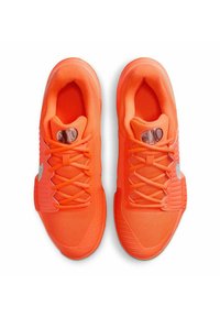 Scarpe sportive di un vivace arancione, con una tomaia in rete, suola in gomma testurizzata e accenti neri sulla linguetta, dotate di un sistema di allacciatura centrale.