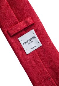 Rode gestippelde stropdas gemaakt van textuurstof. Label bevat "JOHN HENRIC" en "Made in Italy." Het ontwerp omvat een spiraalvormig patroon.