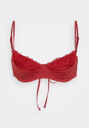 Red underwire bra with adjustable straps, ruched cups, and a tie closure at the front. Smooth fabric with a slight sheen.