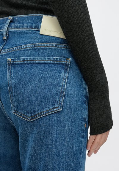 Τζιν τζιν σε μεσαίο μπλε απόχρωση μ�ε υφή επιφάνειας, που διαθέτουν πίσω τσέπη και ετικέτα από δέρμα ανοιχτού χρώματος στη μέση.