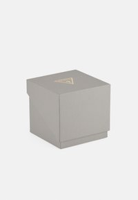 Caja gris texturizada con un logo dorado triangular en la parte superior. Cuenta con una tapa inclinada y una base sólida para el almacenamiento o embalaje.