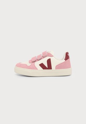 Low-top sneaker met roze suède en wit leer, drie roze klittenbandriemen, rood "V" logo en off-white zool.