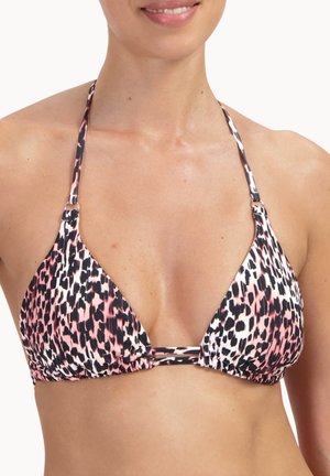 Frau trägt ein Neckholder-Bikinioberteil mit einem abstrakten Leopardenmuster in Pink, Schwarz und Weiß, lächelt sanft.