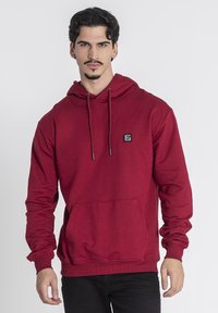 Felpa con cappuccio rosso in cotone misto, dotata di tasca frontale a marsupio, polsini a coste e una piccola etichetta logata nera.