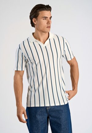Randig polo skjorta i krämfärg med smala marinblå linjer, med en smal krage och korta ärmar. Bärs med denim jeans.
