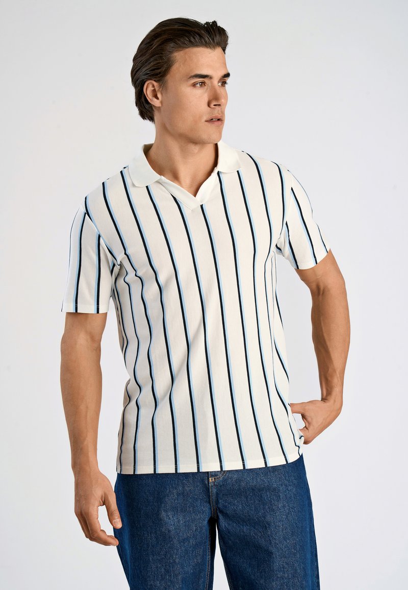 Randig polo skjorta i krämfärg med smala marinblå linjer, med en smal krage och korta ärmar. Bärs med denim jeans.