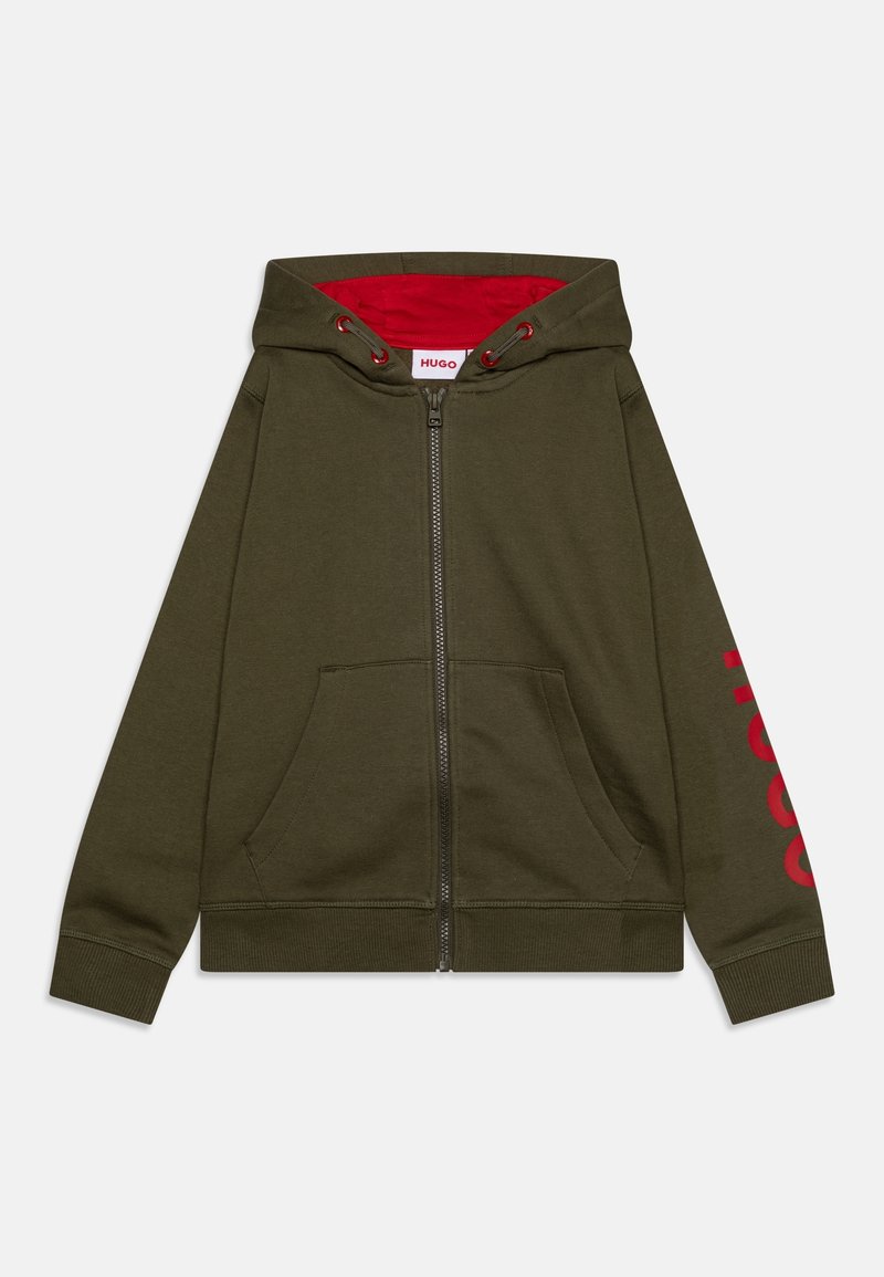 Haut à capuche zippé en vert olive avec une doublure rouge et un grand texte de logo rouge sur la manche gauche. Il possède des poches avant et des poignets côtelés.