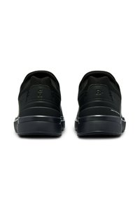 Schwarze Sportschuhe mit einem Mesh-Obermaterial, strukturierten Akzenten, einer gepolsterten Sohle und einem minimalistischen Design mit eingeprägtem Logo-Detail an der Ferse.