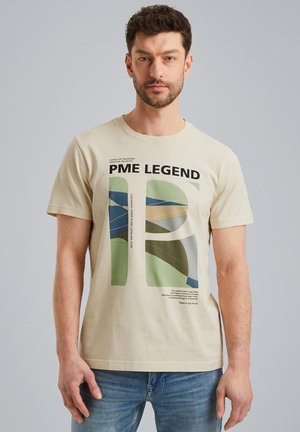 T-shirt en coton beige avec un grand motif graphique en vert, bleu et beige. Manches courtes et encolure ras du cou. Le texte comprend "PME LEGEND."