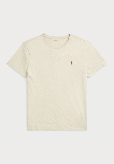 T-shirt beige chiaro realizzato in un morbido tessuto testurizzato. Presenta un collo rotondo e un piccolo logo ricamato marrone sul petto sinistro.