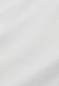 Nahaufnahme eines glatten, weißen Stoffs mit einer subtilen gewebten Textur und sanften Falten, die weiche Schatten erzeugen.