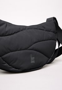 Svart nylonaxelväska med quiltat mönster, med en avtagbar rem. Inkluderar en synlig logga "GOT BAG." på framsidan.
