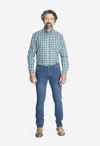 Camisa a cuadros verde y azul, jeans azules y zapatos marrón claro; diseñada para un look casual con una forma ajustada y tejido duradero.