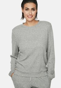 Pull gris côtelé à manches longues et col rond. Le tissu a une texture douce, avec une coupe décontractée et de subtils détails de couture.
