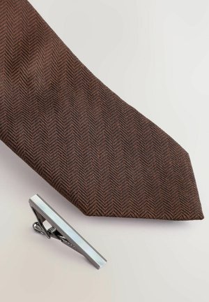 Braune Fischgrätkrawatte aus strukturiertem Stoff, kombiniert mit einer silbernen Krawattennadel mit flacher Kante und glänzender Oberfläche.