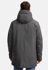 Veste à capuche grise, avec une coupe ample, une texture lisse et un ourlet droit ; elle présente des coutures le long du dos et des manches.