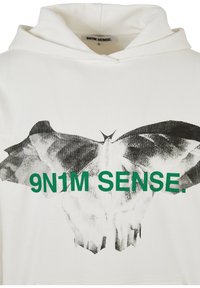 Valkoinen huppari, jossa mustavalkoinen perhosgrafiikka ja vihreä teksti "9N1M SENSE." etupuolella. Pehmeää kangasta, säädettävä huppu.