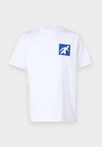 Balta medvilnės marškinėliai su laisvu pjūviu, ant kurių kairėje krūtinės pusėje yra mėlyna kvadrato grafika su balta figūros siluetu.