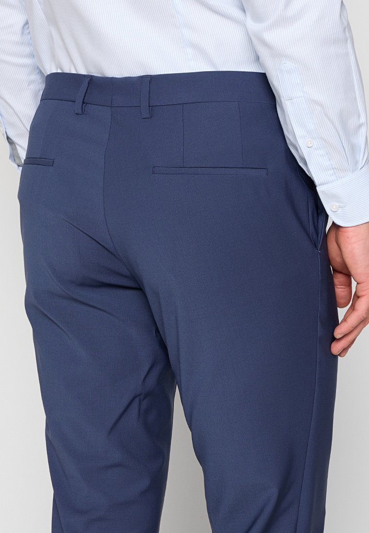 Pantaloni navy con una vestibilità sartoriale, dotati di due tasche posteriori e un tessuto liscio e testurizzato. Progettati con una vita classica.