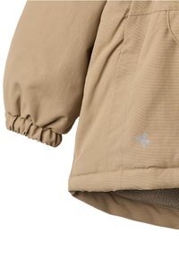 Béžová bunda z texturované látky, s elastickým manžetem a fleecovou podšívkou na lemu. Malé ražené logo na boku dodává detail.