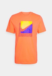 Světlé oranžové tričko s krátkým rukávem se čtvercovou grafikou s fialovým a modrým designem Nike swoosh uprostřed.